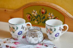 three cups and a glass container sitting on a table at Historisches Gästehaus Au Faucon von 1535 in Wissembourg