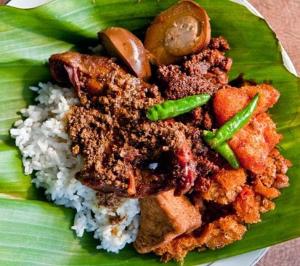 a plate of food with rice and vegetables on a leaf at Kampoeng Joglo Boutique Hotel in Yogyakarta