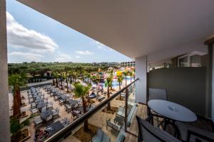 einen Balkon mit Blick auf ein Resort mit Pool und Palmen in der Unterkunft Caretta Paradise Resort & WaterPark in Tragaki