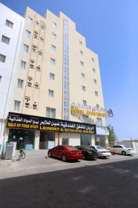 un gran edificio con coches estacionados frente a él en Al Rayyan Hotel Apartments Muscat, en Seeb