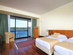 een hotelkamer met 2 bedden en een groot raam bij Hotel Salò du Parc in Salò