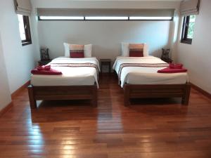 two beds in a room with wooden floors at Koh Phangan Pavilions Serviced Apartments in Thong Nai Pan Noi