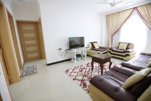 een woonkamer met 2 banken en een tv bij Al Rayyan Hotel Apartments Muscat in Seeb