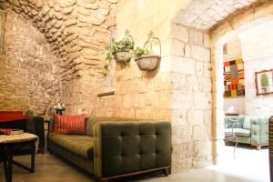 a living room with a couch against a stone wall at Al-Hakim Boutique Hotel Old Town Nazareth in Nazareth