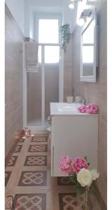 a white bathroom with a sink and flowers in it at CASACRIZIA in Cagliari