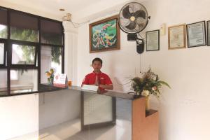 un hombre sentado en un mostrador en una habitación en OYO 1456 Hotel Garuda, en Lampung