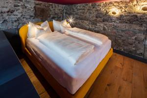 1 cama con sábanas blancas y almohadas en una habitación en Flurin Suites, en Glorenza