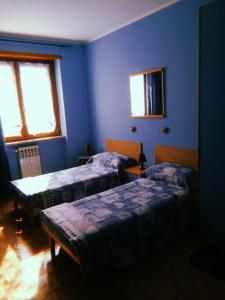 een blauwe kamer met 2 bedden en een raam bij au montfleury in Aosta