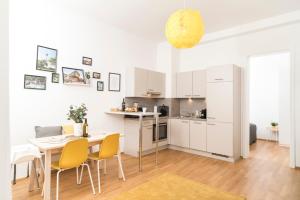 kuchnia i jadalnia ze stołem i żółtymi krzesłami w obiekcie Prater Balcony Suite w Wiedniu