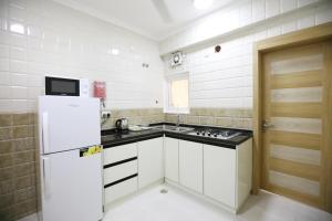 a kitchen with a white refrigerator and a sink at Al Rayyan Hotel Apartments Muscat in Seeb