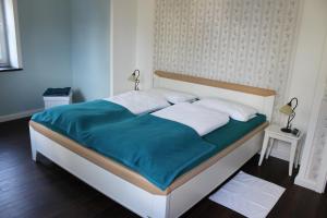 1 cama con manta azul y almohadas blancas en Ferienwohnung Ostwind, en Schüller