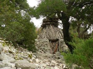 a small building on a rocky hill with a tree at Hotel Bia Maore in Baunei
