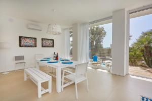 a white dining room with a white table and chairs at CASA sugli SCOGLI in Fontane Bianche