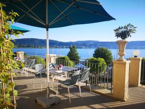 un patio con mesa, sillas y sombrilla en Seehotel Villa Linde, en Bodman-Ludwigshafen