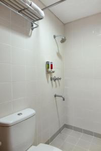 a white bathroom with a toilet and a shower at Amaris Hotel Pemuda Semarang in Semarang