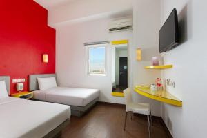 a room with two beds and a desk and a tv at Amaris Hotel Pemuda Semarang in Semarang