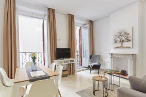 a living room with a table and chairs and a tv at LEEWAYS APARTMENT XVIII in GRAN VÍA in Madrid