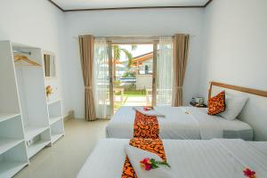a bedroom with two beds and a sliding glass door at Rumah Marta Ceningan Island in Nusa Lembongan