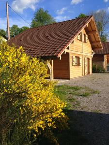una casa con techo marrón y flores amarillas en Le Chalet des Neiges, en Thiéfosse