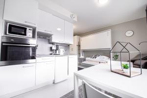 a kitchen with white cabinets and a white counter top at Spot Apartments Rajakylä in Vantaa