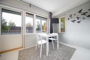 a dining room with a table and chairs and windows at Spot Apartments Rajakylä in Vantaa