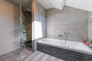 a bathroom with a tub and a glass shower at Le Clocher in Nassogne