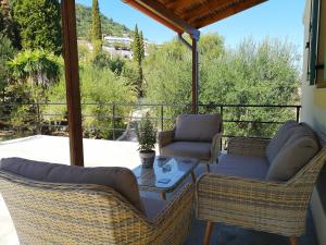 a porch with two chairs and a table with a view at Nikoli Apartments in Benitses