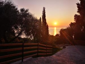 a sunset over the ocean with a fence at Nikoli Apartments in Benitses