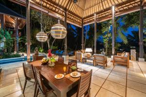 an outdoor dining room with a table and chairs at Villa Vajra in Ubud