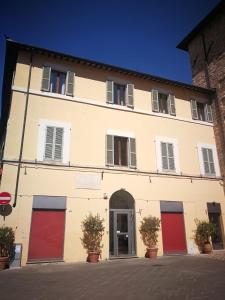 - un grand bâtiment blanc avec des portes et des fenêtres rouges dans l'établissement St Francis Apartaments, à Foligno