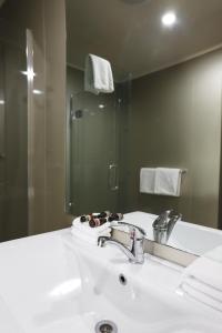 a bathroom with a white sink and a mirror at Airport Manor Inn in Auckland