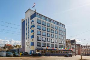 Un grand bâtiment blanc avec des drapeaux en haut dans l'établissement Badhotel The Hague Scheveningen, à Scheveningen