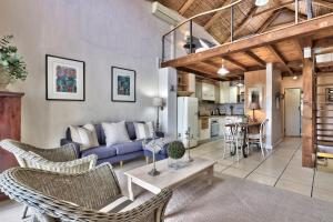 a living room with a couch and chairs and a table at The Beach Loft in Hout Bay