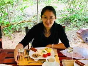 une femme assise à une table avec une assiette de nourriture dans l'établissement Yala Leopard Mobile Camp, à Yala