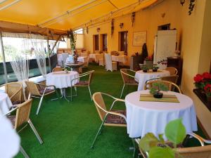 un restaurante con mesas blancas y sillas sobre alfombra verde en Hotel Oko, en Nitra