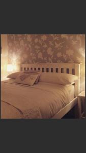 a bedroom with a white bed with floral wallpaper at Ty Mawr Hotel in Llanbedr