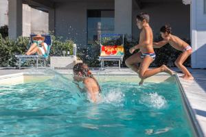 een groep jongens die in een zwembad spelen bij Terraces d'Orlando - Family Apartments with Sea View and Pool in Capo dʼOrlando