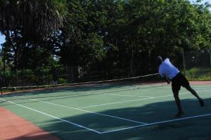 
a man swinging a tennis racquet on a tennis court at Jacaranda Indian Ocean Beach Resort in Diani Beach
