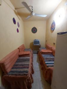 a living room with three beds and a ceiling fan at Otasho Nile view house in Aswan