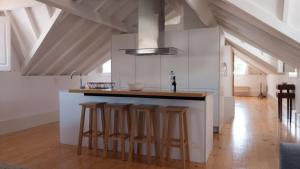 eine Küche mit weißen Schränken und einer Theke mit Stühlen in der Unterkunft APOSENTUS - Architect and design apartment in Porto