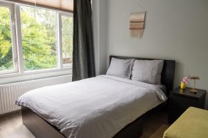 een slaapkamer met een bed met witte lakens en een raam bij CityTreeHouse ApartHotel in Arnhem