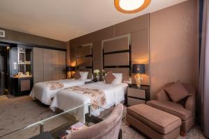 een hotelkamer met 2 bedden en een stoel bij New World Suites in Bintulu