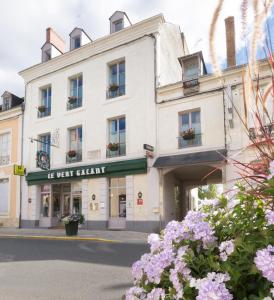 Un bâtiment blanc avec des fleurs devant lui dans l'établissement Logis Hôtel Le Vert Galant, à La Flèche