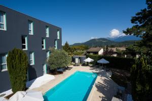 a swimming pool in front of a building at PoMo Hôtel & Restaurant in Échirolles