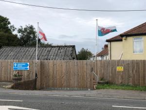 two flags flying in front of a wooden fence at 1 Ashford Road Guesthouse in Redhill