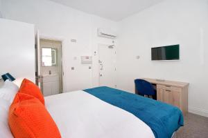 a bedroom with a bed with orange pillows and a desk at Interlude House A by City Living London in London