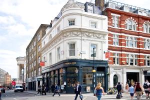 um grupo de pessoas atravessando uma rua em frente a um edifício em Interlude House C by City Living London em Londres