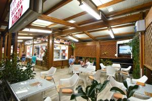 a restaurant with white chairs and tables and people sitting at tables at Hotel Galeb in Čanj