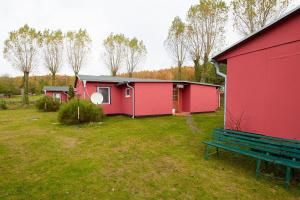 ein rotes Haus und eine Bank in einem Hof in der Unterkunft Familienzimmer mit Gemeinschaftsbad in Groß Banzelvitz