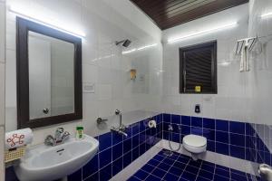 a bathroom with a sink and a toilet and a mirror at SaffronStays Blue Flag House, a 3-BDR beachfront villa in Hejamady in Mangalore